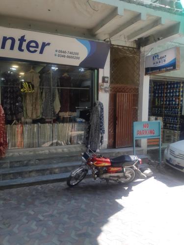 una moto parcheggiata di fronte a un negozio di abbigliamento di Shah Residence a Khwāzakhela