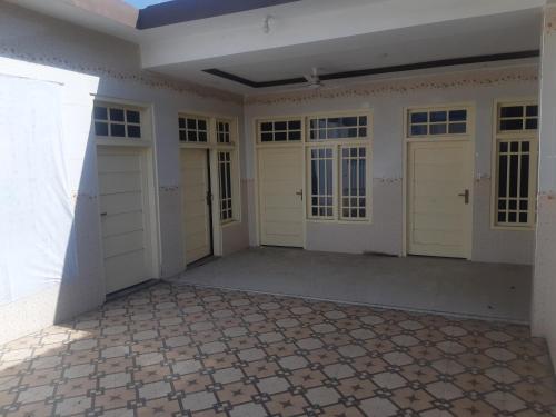 een grote kamer met 3 garagedeuren en een tegelvloer bij Shah Residence in Khwāzakhela