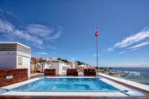 una piscina en la parte superior de una casa con el océano en Sud Ibiza Suites en Ibiza