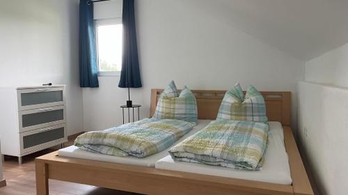 1 dormitorio con 1 cama con 2 almohadas y ventana en Ferienwohnung am Bauernhof, en Wald