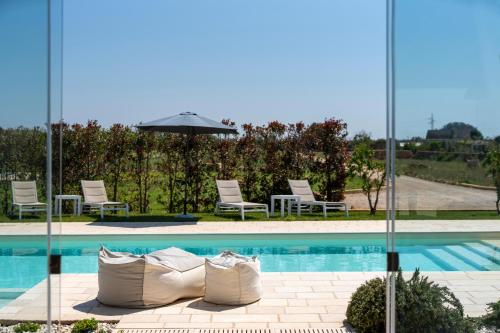 a swimming pool with chairs and an umbrella at Villa Lucia - Exclusive Private Pool in Gallipoli