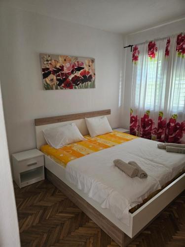 a bedroom with a bed with white sheets and curtains at Apartman Ljubo in Podgora
