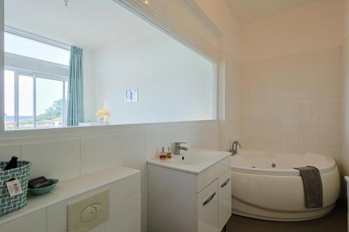 Baño blanco con bañera y lavamanos en Apartment Tiki Plage mit Meerblick und direkt am Strand, en Saint-Raphaël