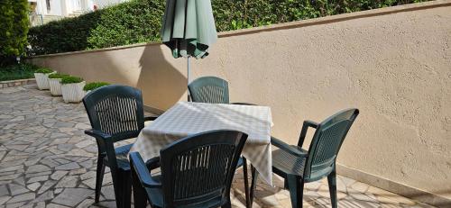 uma mesa com quatro cadeiras e um guarda-sol verde em Apartment LAGUNA 22 em Izola