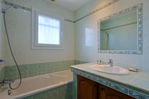 une salle de bain avec un lavabo, une baignoire et un miroir dans l'établissement Provenzalische Villa l'Olivier - mit Terrasse und privatem Pool by Riviera HomeLife, à Saint-Raphaël