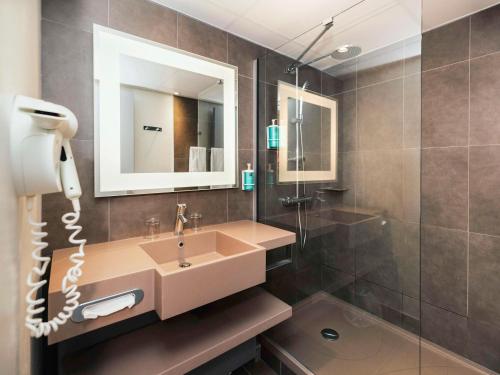 La salle de bains est pourvue d'un lavabo et d'un miroir. dans l'établissement Novotel Clermont-Ferrand, à Clermont-Ferrand