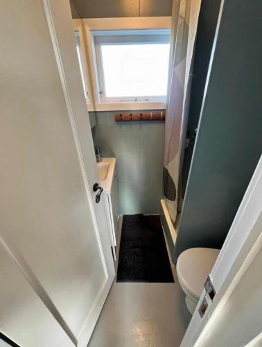 a small bathroom with a toilet and a window at Nónhóll - Ocean View Cottage in Arnarstapi in Stapi