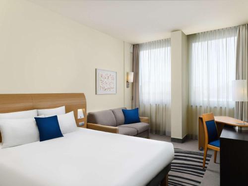 una camera d'albergo con un grande letto e una scrivania di Novotel Budapest Danube a Budapest