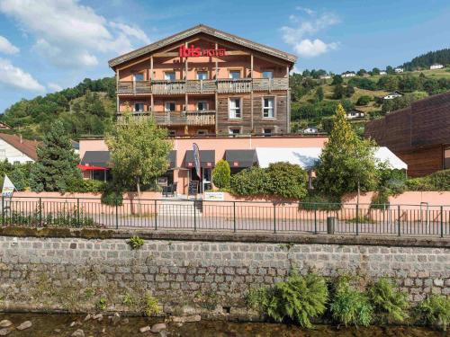 a building with a fence in front of a river at ibis La Bresse Gérardmer in La Bresse