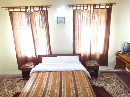 a bedroom with a bed with curtains and a television at Noorband Qalla Hotel,Bamyan 