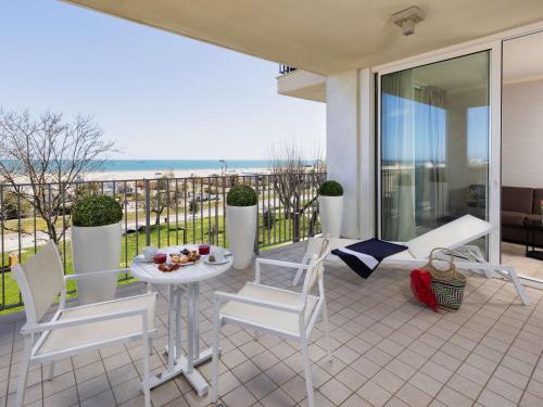 einen Balkon mit einem Tisch, Stühlen und Meerblick in der Unterkunft Mercure Rimini Lungomare in Rimini