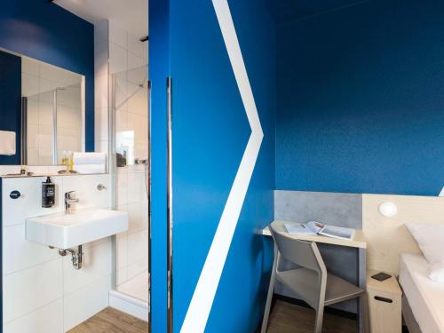ein Badezimmer mit einem weißen Waschbecken und einer blauen Wand in der Unterkunft ibis budget Ludwigsburg -RENOVIERT IN 2024!- in Ludwigsburg
