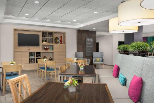 a waiting room with tables and chairs and a tv at Home2 Suites by Hilton Knoxville West in Knoxville