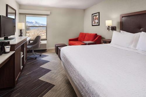 Habitación de hotel con cama, escritorio y TV. en Hampton Inn Taos, en Taos