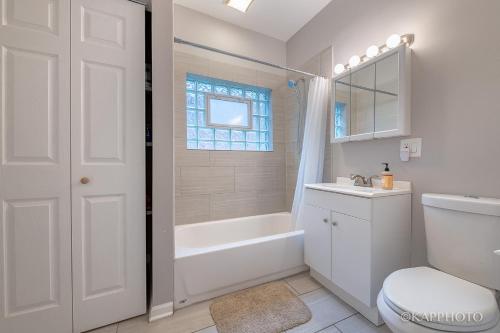 a white bathroom with a tub and a toilet and a sink at Wonderful Home Close to Downtown Chicago - Free Parking in Chicago
