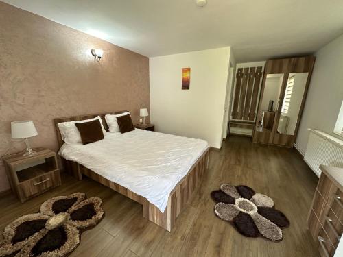 a bedroom with a bed with white sheets and two rugs at Casa Antonia in Chişcău