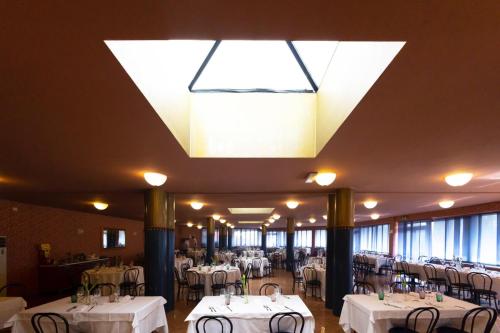 um restaurante com mesas e cadeiras brancas e um lustre em HOTEL BRUNFORTE em Sarnano