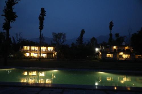 a house and a swimming pool at night at Hideaway By Aahma in Rāmnagar