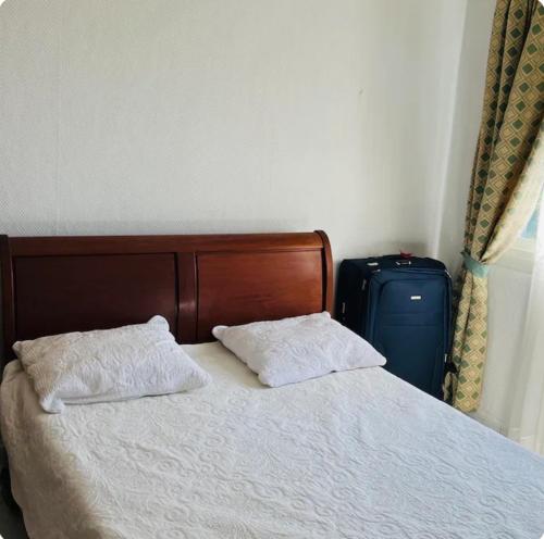 a bed with two pillows and a suitcase in a bedroom at Villa des écuries BENARD in Sainte-Suzanne