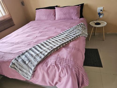a pink bed with a blanket on top of it at Donsie Guesthouse in Nqutu