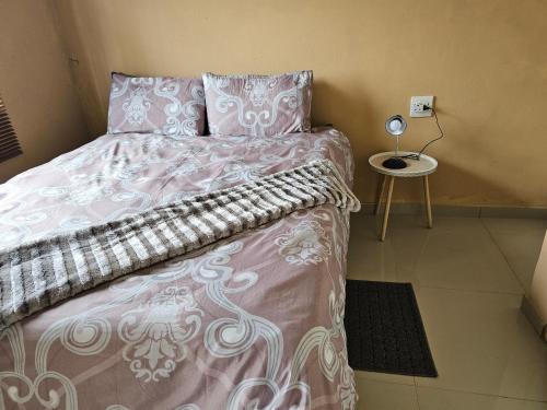 a bedroom with a bed with pink and white sheets and a table at Donsie Guesthouse in Nqutu
