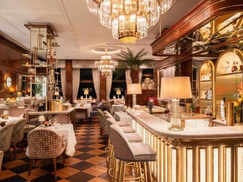 un restaurante con mesas y sillas y una lámpara de araña en Fairmont Hotel Vier Jahreszeiten, Hotel des Jahres 2023 & 2024- Die 101 Besten en Hamburgo