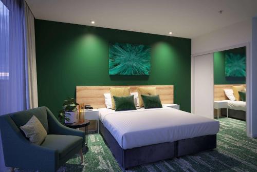 a bedroom with a large bed and a chair at La Quinta by Wyndham Ellerslie Auckland in Auckland