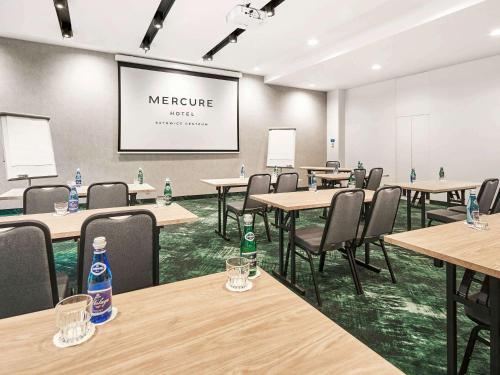 a conference room with tables and chairs and a screen at Mercure Katowice Centrum in Katowice