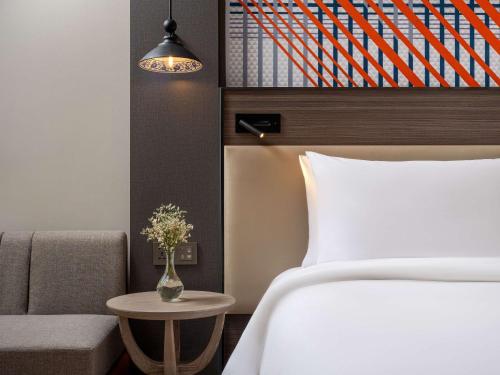 a bedroom with a bed and a chair and a table at Mercure Bangkok Surawong in Bangkok