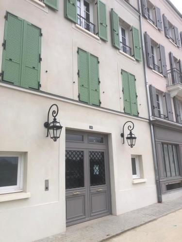a building with green shuttered windows and a door at Disneyland-Paris - 5 pers Netflix, Parking, Wifi in Serris