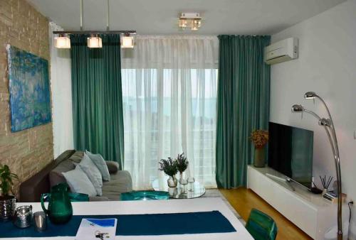 a living room with a large window with green curtains at Bubbles Penthouse with Jacuzzi in Podstrana