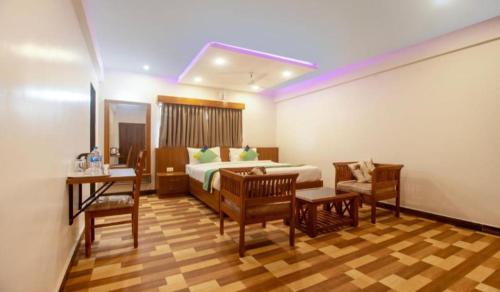 1 dormitorio con 1 cama, mesa y sillas en Valley Plaza Hotel Coorg en Madikeri