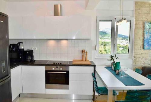 a kitchen with white cabinets and a table with a counter top at Bubbles Penthouse with Jacuzzi in Podstrana