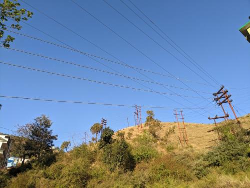 a hill with power lines on top of it at Krishna Homestay Nohradhar in Tārna