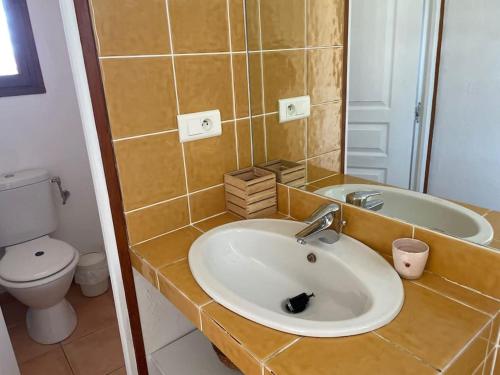 a bathroom with a sink and a toilet and a mirror at Charmante maison de village in Porto-Vecchio