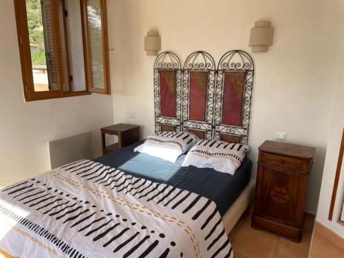 Schlafzimmer mit einem Bett mit einer schwarzen und weißen Bettdecke in der Unterkunft Charmante maison de village in Porto-Vecchio