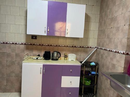 uma cozinha com armários roxos e brancos e um lavatório em Cozy Nile view apartment em Asyut