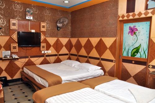 a bedroom with two beds and a tv in it at Hotel Shri Swarna's Palace - A Business Class Hotel in Tiruchchirāppalli