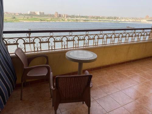 una mesa y 2 sillas en un balcón con vistas al agua en Cozy Nile view apartment, en Asiut