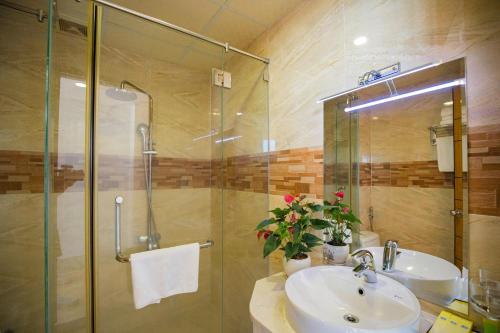 ein Bad mit einem Waschbecken und einer Glasdusche in der Unterkunft Happy Light Hotel Nha Trang in Nha Trang