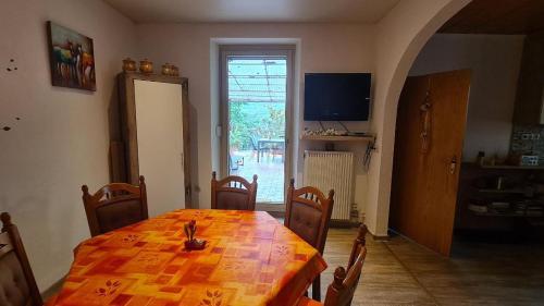 a dining room with a wooden table and a television at FeWo Nitteler Zauberpfoten in Nittel