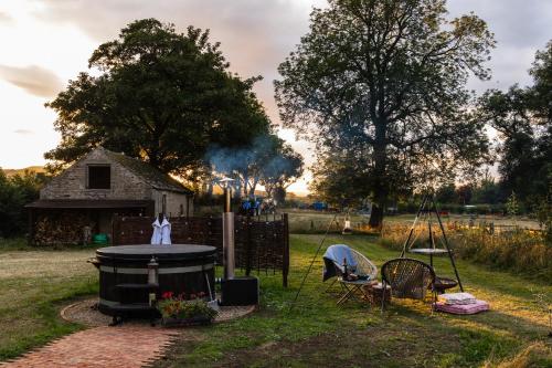 a grill in a yard with a house in the background at Toadland Shepherd Huts in Durham