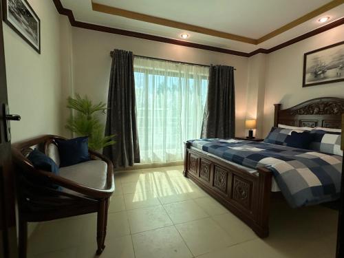 um quarto com uma cama, uma cadeira e uma janela em Shaiz Apartments Bhurban, Murree em Murree