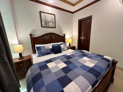 a bedroom with a blue and white bed and two lamps at Shaiz Apartments Bhurban, Murree in Murree