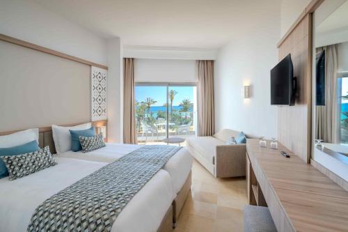 TUI BLUE Palm Beach Hammamet في الحمامات: غرفة فندقية بسرير كبير واريكة