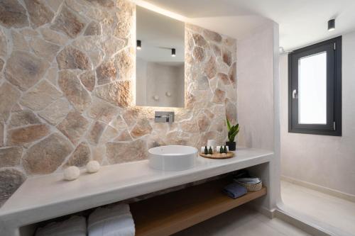 uma casa de banho com um lavatório e uma parede de pedra em CUORE SANTO SUITES em Fira