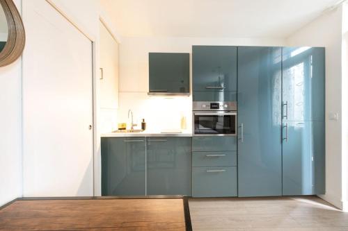 een keuken met blauwe kasten en een koelkast bij Chaleureux Studio 2 pers in Lyon