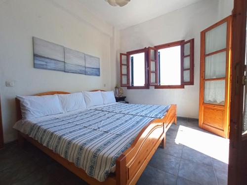 a bedroom with a bed in a room with windows at Katafigio Home in Tsagkarada Village in Tsagarada