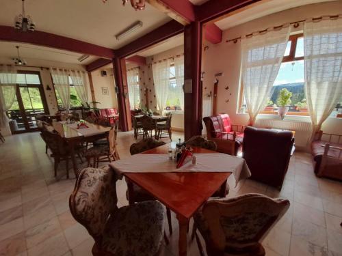 a dining room with tables and chairs and windows at Vila Riki in Borsec