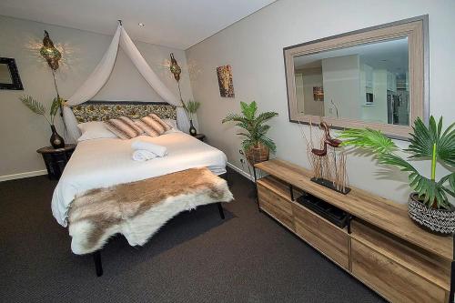 a bedroom with a large bed with a large mirror at Brighton Shores 1 bedroom apartment in Gold Coast